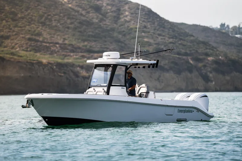Shark Bait Yacht Photos Pics 2025 Everglades 285 Center Console boat on water, with scenic rocky background.