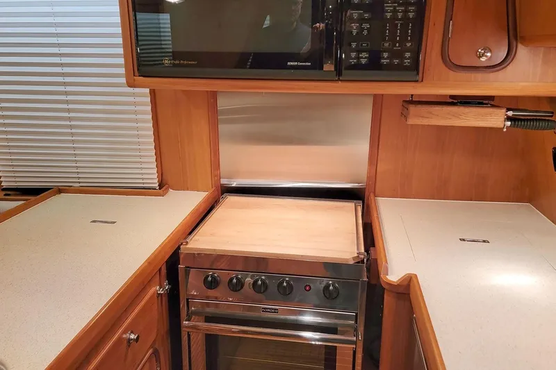 Carolina Yacht Photos Pics 2001 Nordhavn 46 yacht kitchen with stove, microwave, and wooden cabinetry.
