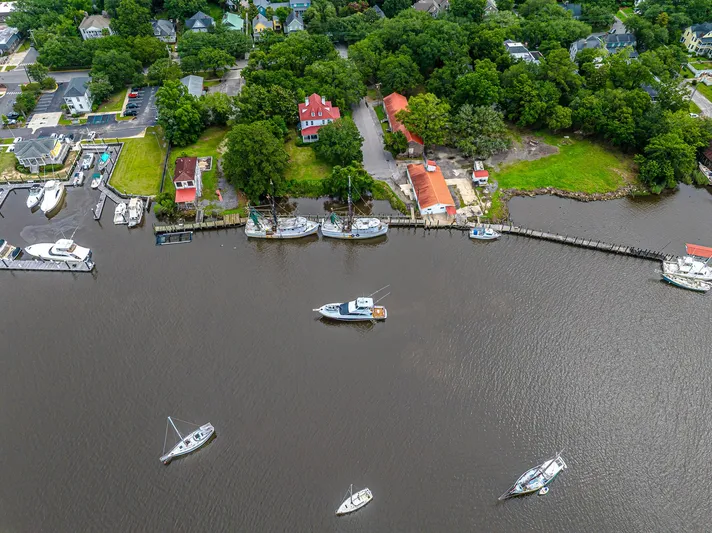 Double Down Yacht Photos Pics Aerial view of boats docked along a river, surrounded by lush greenery and residential buildings.