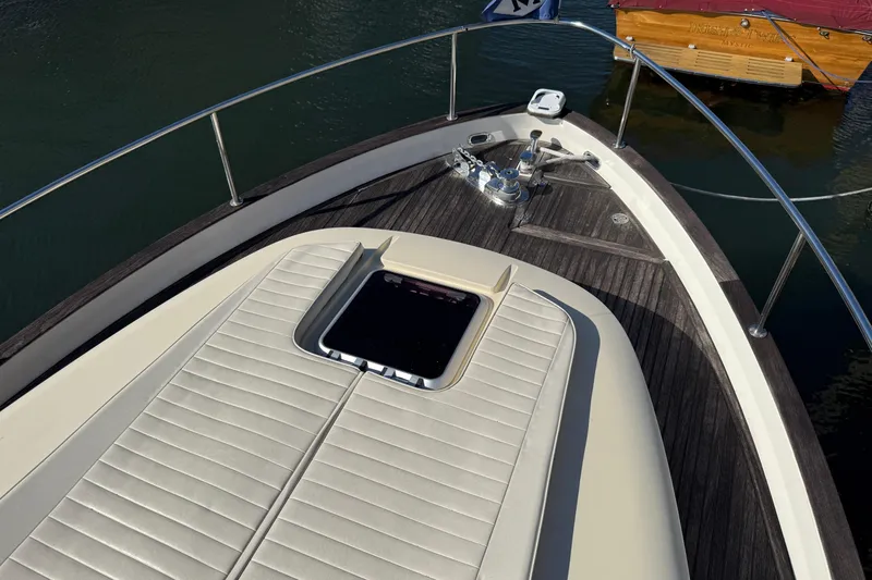 Landfall Yacht Photos Pics Bow of 2013 Greenline 33 yacht with sunpad and anchor, docked on calm water.