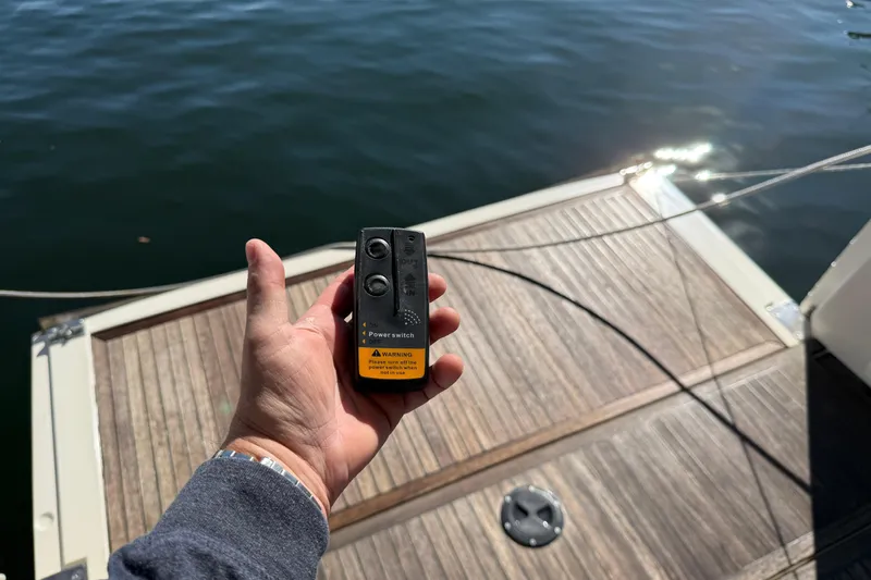 Landfall Yacht Photos Pics Hand holding a remote control on a 2013 Greenline 33 yacht deck by the water.