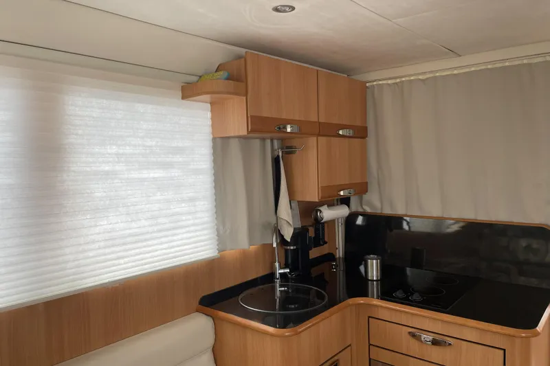 Landfall Yacht Photos Pics Compact kitchen interior of 2013 Greenline 33 boat with wooden cabinets and modern appliances.