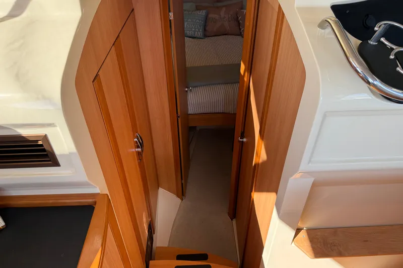 Landfall Yacht Photos Pics Interior view of 2013 Greenline 33 yacht, featuring wooden cabinetry and cozy sleeping area.