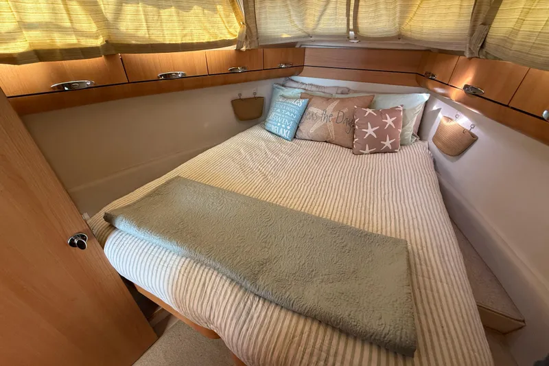 Landfall Yacht Photos Pics Cozy bedroom interior of 2013 Greenline 33 yacht with decorative pillows and wooden cabinets.