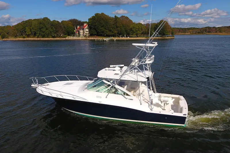 Moving Violation Yacht Photos Pics 2008 Cabo 40 boat cruising on a scenic lake with a wooded shoreline.