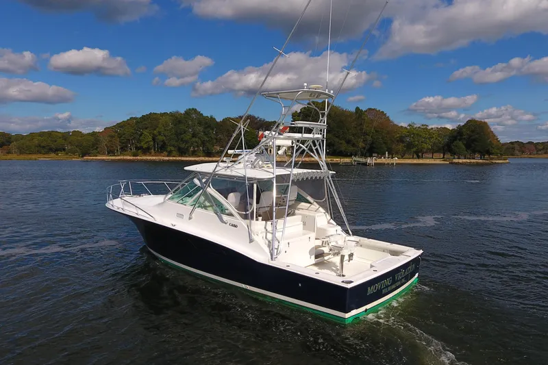 Moving Violation Yacht Photos Pics 2008 Cabo 40 boat cruising on a scenic lake under a partly cloudy sky.