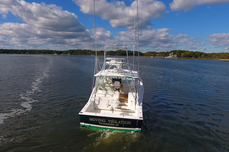 Moving Violation Yacht Photos Pics 2008 Cabo 40 boat cruising on a calm lake under a partly cloudy sky.