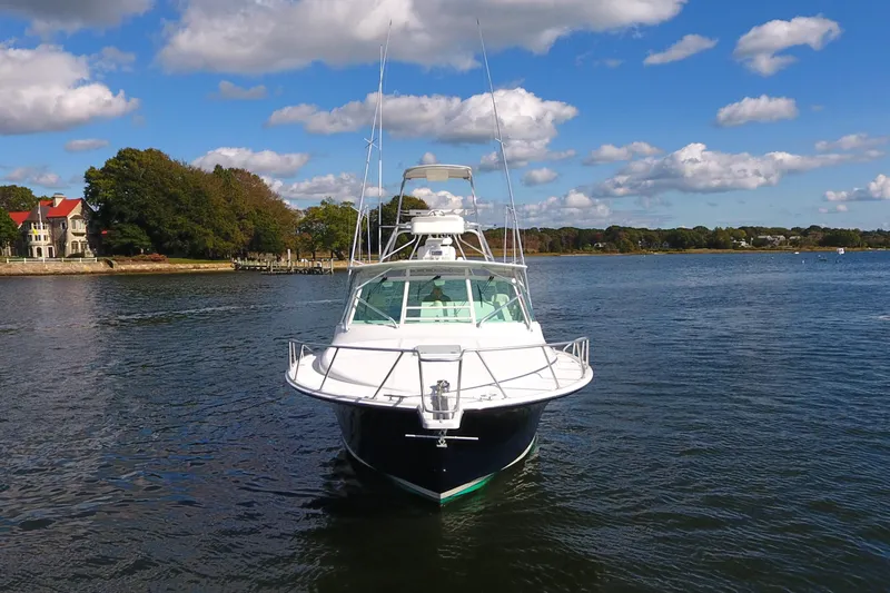 Moving Violation Yacht Photos Pics 2008 Cabo 40 boat on calm water with scenic shoreline and blue sky.