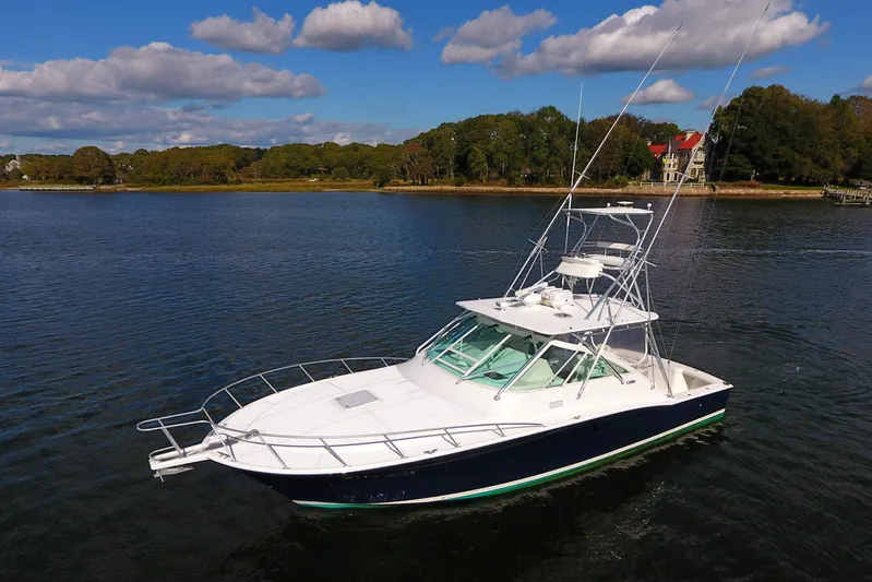 Moving Violation Yacht Photos Pics 2008 Cabo 40 boat on calm water with scenic shoreline background.