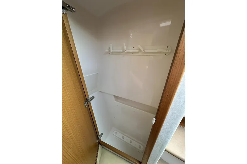 Moving Violation Yacht Photos Pics Empty storage closet inside 2008 Cabo 40 boat, featuring wooden door and wall hooks.