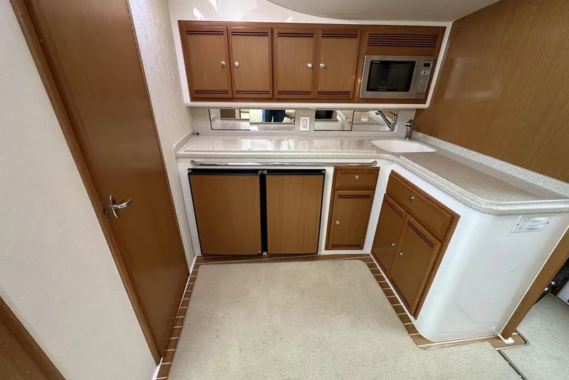 Moving Violation Yacht Photos Pics Compact kitchen in a 2008 Cabo 40 boat with wooden cabinets and modern appliances.