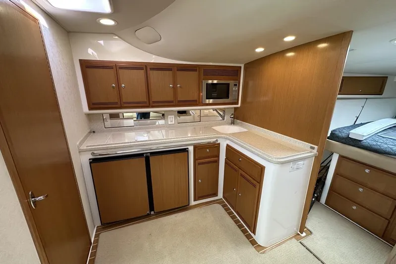 Moving Violation Yacht Photos Pics 2008 Cabo 40 yacht interior kitchen with wooden cabinets, microwave, and compact fridge.