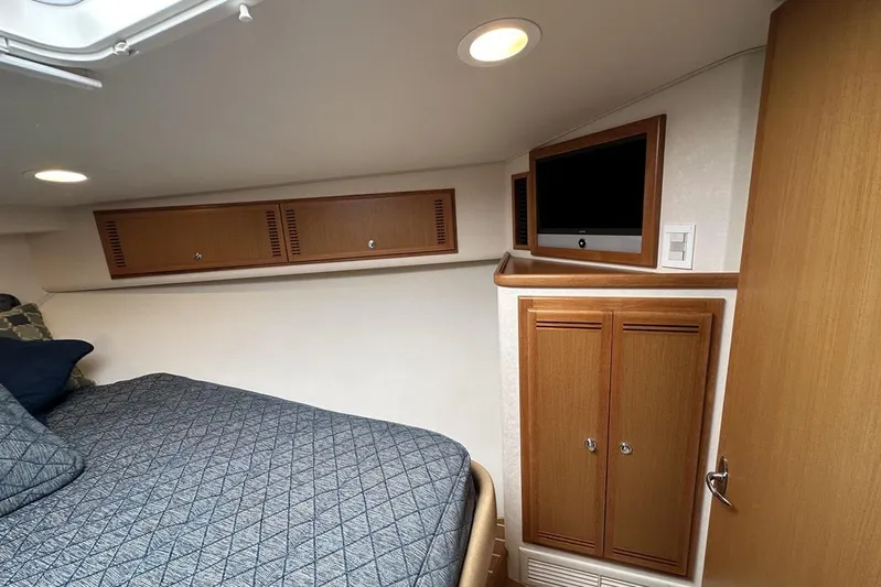 Moving Violation Yacht Photos Pics 2008 Cabo 40 interior cabin with bed, TV, and wooden storage cabinets.