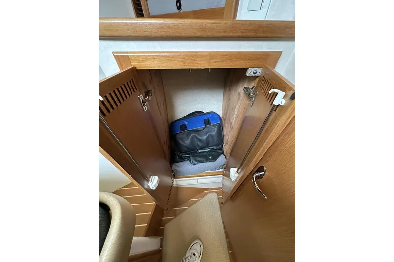 Moving Violation Yacht Photos Pics Wooden cabinet interior on a 2008 Cabo 40 boat, storing a blue and black bag.