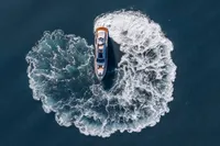 Aerial view of 2020 Pershing 8X yacht making a circular wake in the ocean.