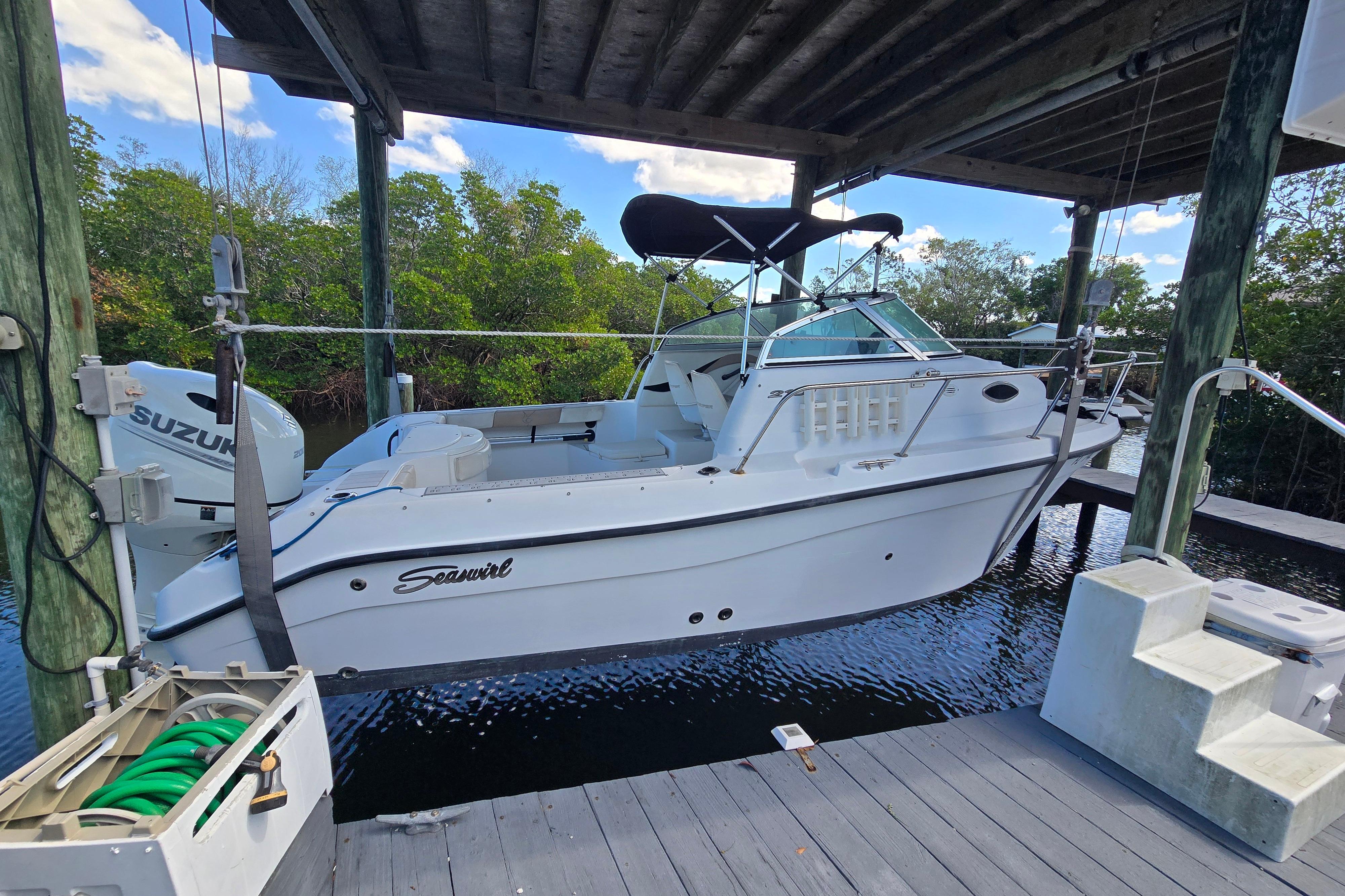 2004 Seaswirl Striper 2101 Walkaround O/B boat docked under a wooden canopy.