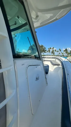  Yacht Photos Pics 2014 Boston Whaler 350 Outrage boat, side view, with clear blue sky and palm trees.