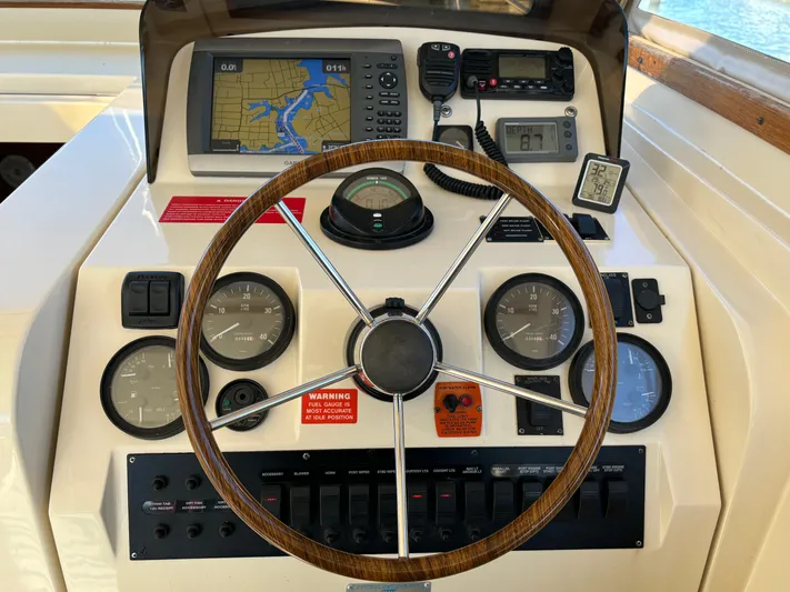 Bay Cruzin Yacht Photos Pics Helm of 2004 Mainship Pilot 34 Rum Runner II Hardtop with navigation instruments and wooden steering wheel.