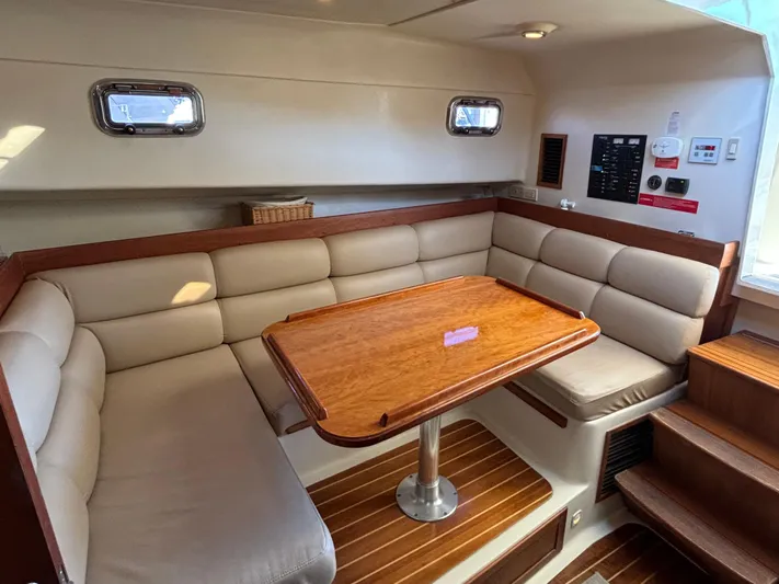 Bay Cruzin Yacht Photos Pics 2004 Mainship Pilot 34 Rum Runner II Hardtop interior with cushioned seating and wooden table.