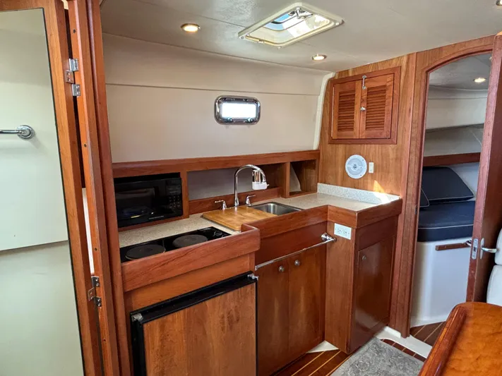 Bay Cruzin Yacht Photos Pics 2004 Mainship Pilot 34 Rum Runner II Hardtop interior with wood cabinetry and compact kitchen.