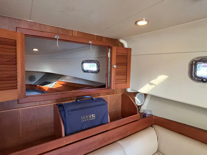Bay Cruzin Yacht Photos Pics 2004 Mainship Pilot 34 Rum Runner II cabin interior with wooden cabinetry and porthole window.