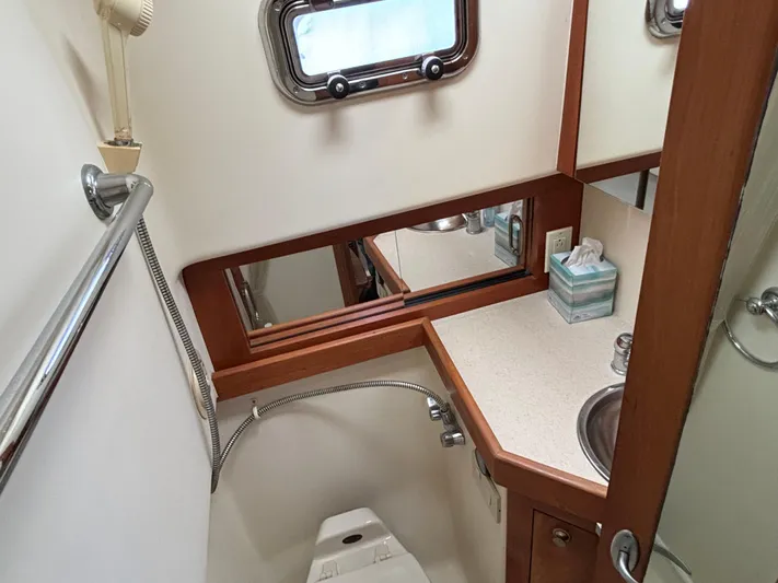 Bay Cruzin Yacht Photos Pics 2004 Mainship Pilot 34 Rum Runner II Hardtop bathroom with sink, mirror, and porthole window.