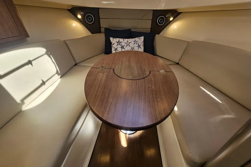 Day For It Yacht Photos Pics 2018 Boston Whaler 315 Conquest cabin interior with cozy seating and wooden table.