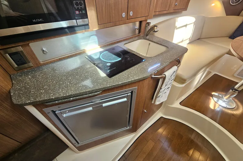 Day For It Yacht Photos Pics 2018 Boston Whaler 315 Conquest interior kitchen with sink, stove, and seating area.