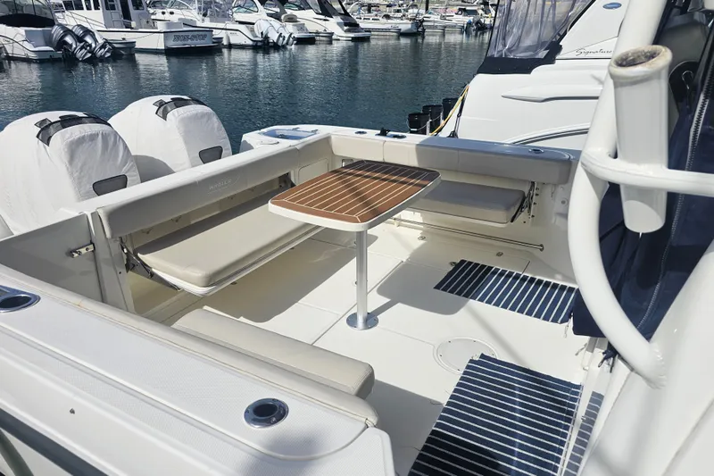 Day For It Yacht Photos Pics 2018 Boston Whaler 315 Conquest boat interior with seating and table, docked at marina.