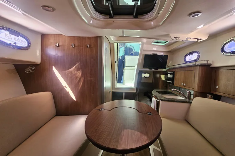 Day For It Yacht Photos Pics 2018 Boston Whaler 315 Conquest cabin interior with seating, table, and kitchenette.