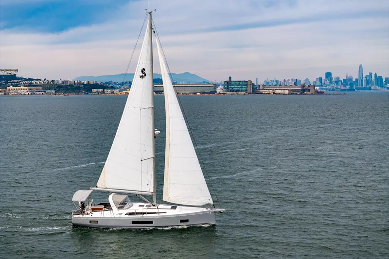 Cypress And Star II Yacht Photos Pics 2020 Beneteau Oceanis 46.1 sailing near urban skyline, under clear skies.