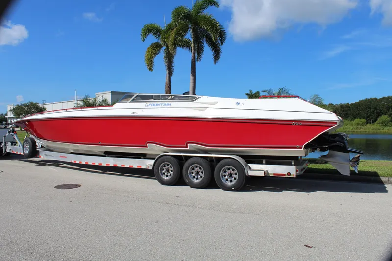 Lightning Yacht Photos Pics 2007 Fountain 42 Lightning speedboat on trailer, red and white, parked near palm trees.