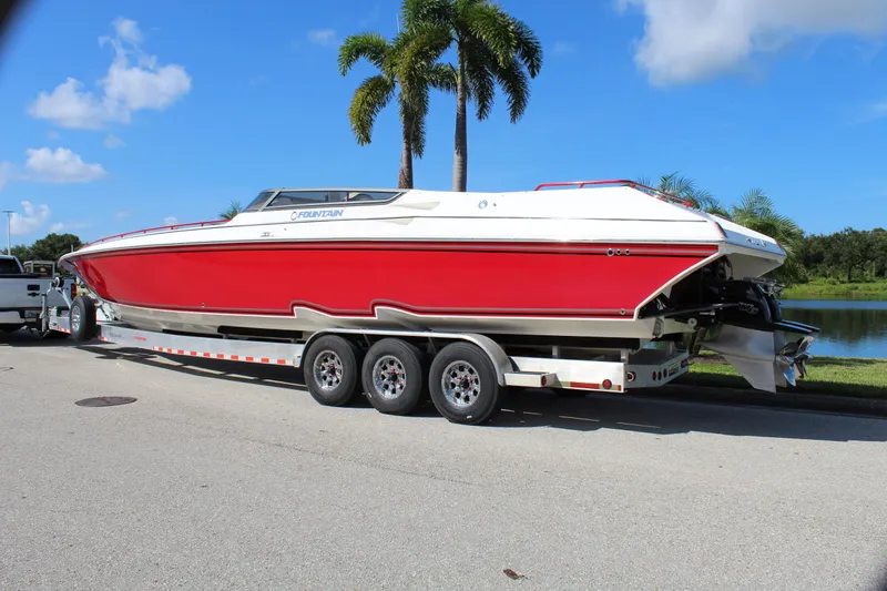 Lightning Yacht Photos Pics 2007 Fountain 42 Lightning boat on trailer, red and white, parked near palm trees.
