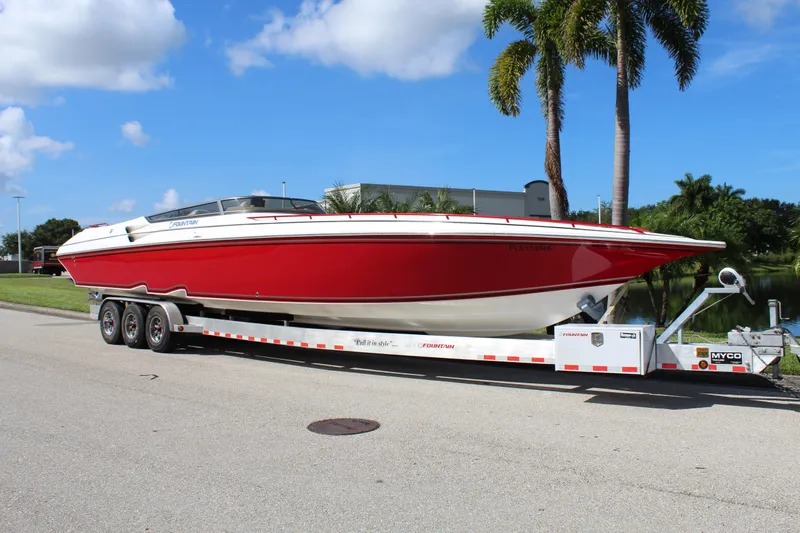 Lightning Yacht Photos Pics 2007 Fountain 42 Lightning boat on trailer, red and white, parked near palm trees.
