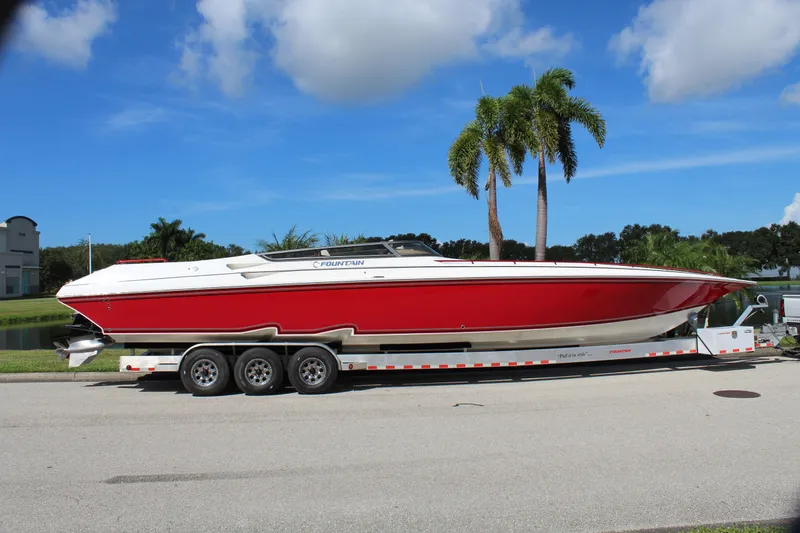 Lightning Yacht Photos Pics 2007 Fountain 42 Lightning speedboat on trailer, red and white, parked near palm trees.