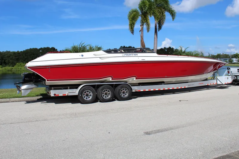 Lightning Yacht Photos Pics 2007 Fountain 42 Lightning speedboat on trailer, red and white, parked near palm trees.