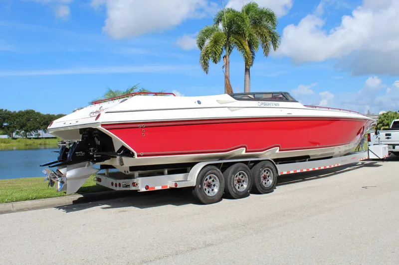 Lightning Yacht Photos Pics 2007 Fountain 42 Lightning speedboat on trailer, red and white design, parked near palm trees.