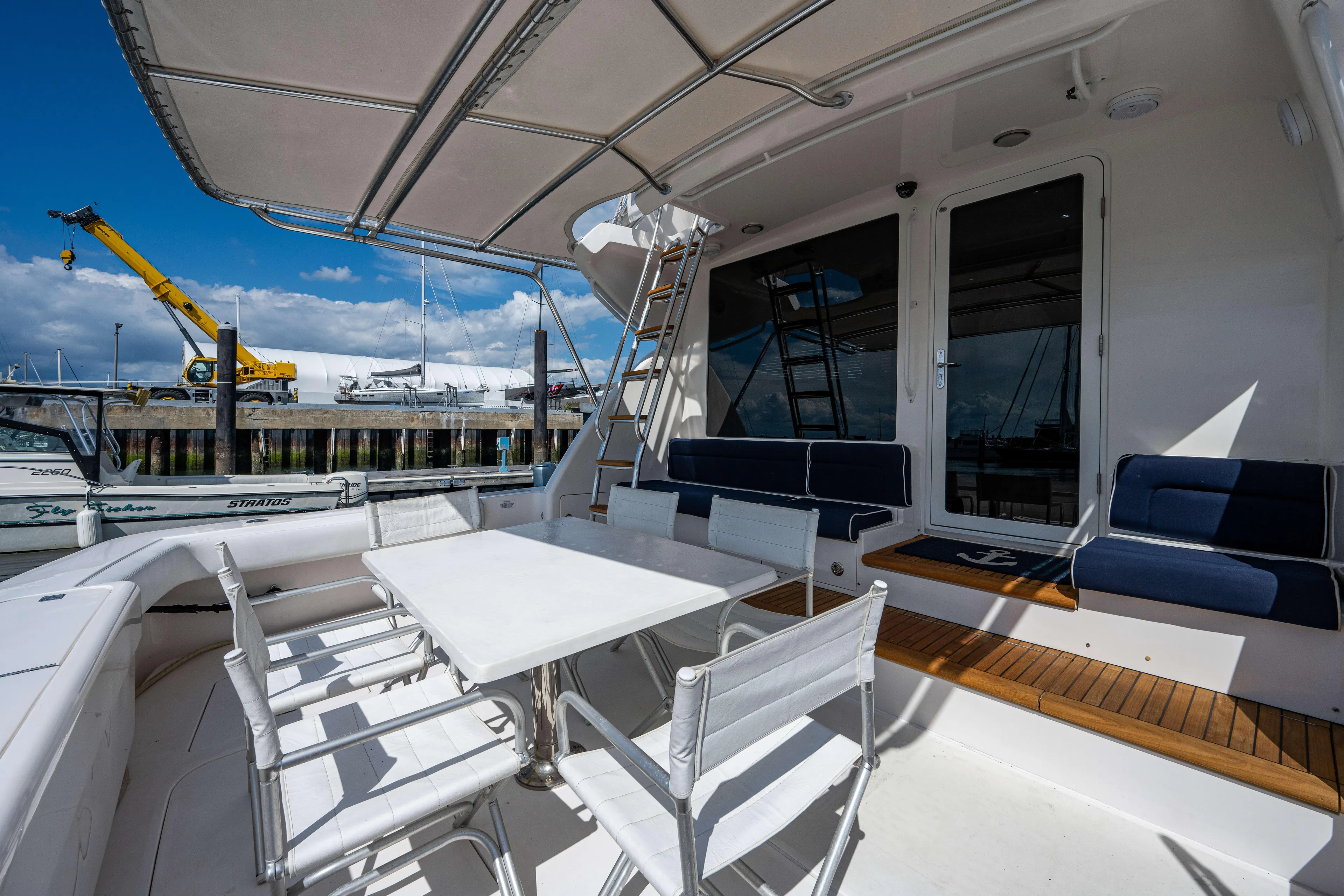 Nine Yacht Photos Pics Luxury 2008 Bertram 570 yacht deck with seating and table, docked at marina.