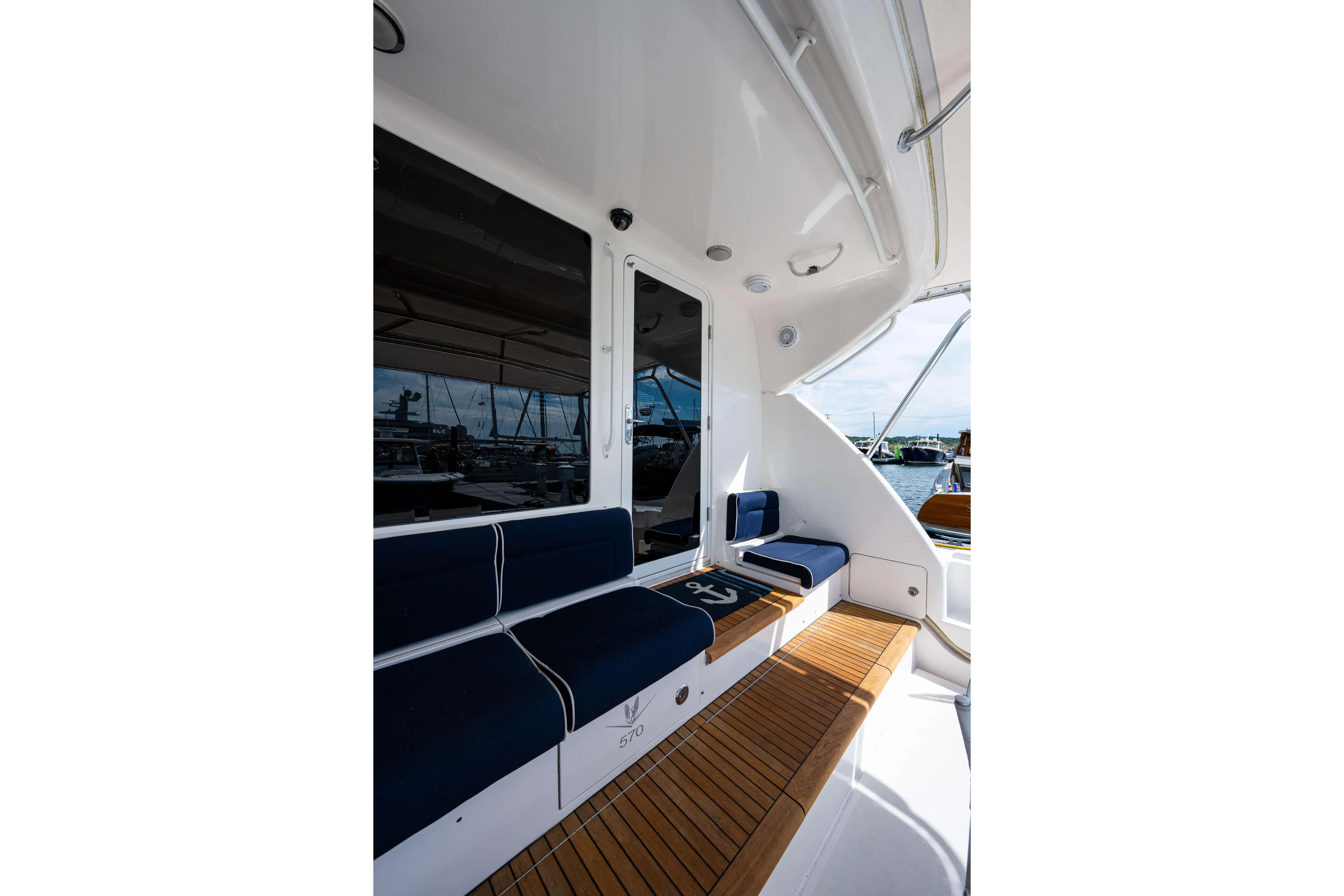 Nine Yacht Photos Pics 2008 Bertram 570 yacht deck with blue seating and wooden flooring.