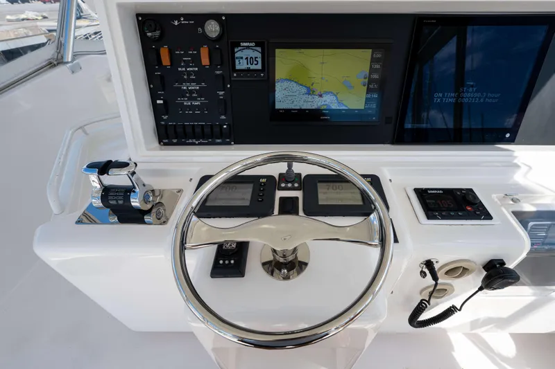 Nine Yacht Photos Pics Control panel of a 2008 Bertram 570 yacht with navigation screens and steering wheel.