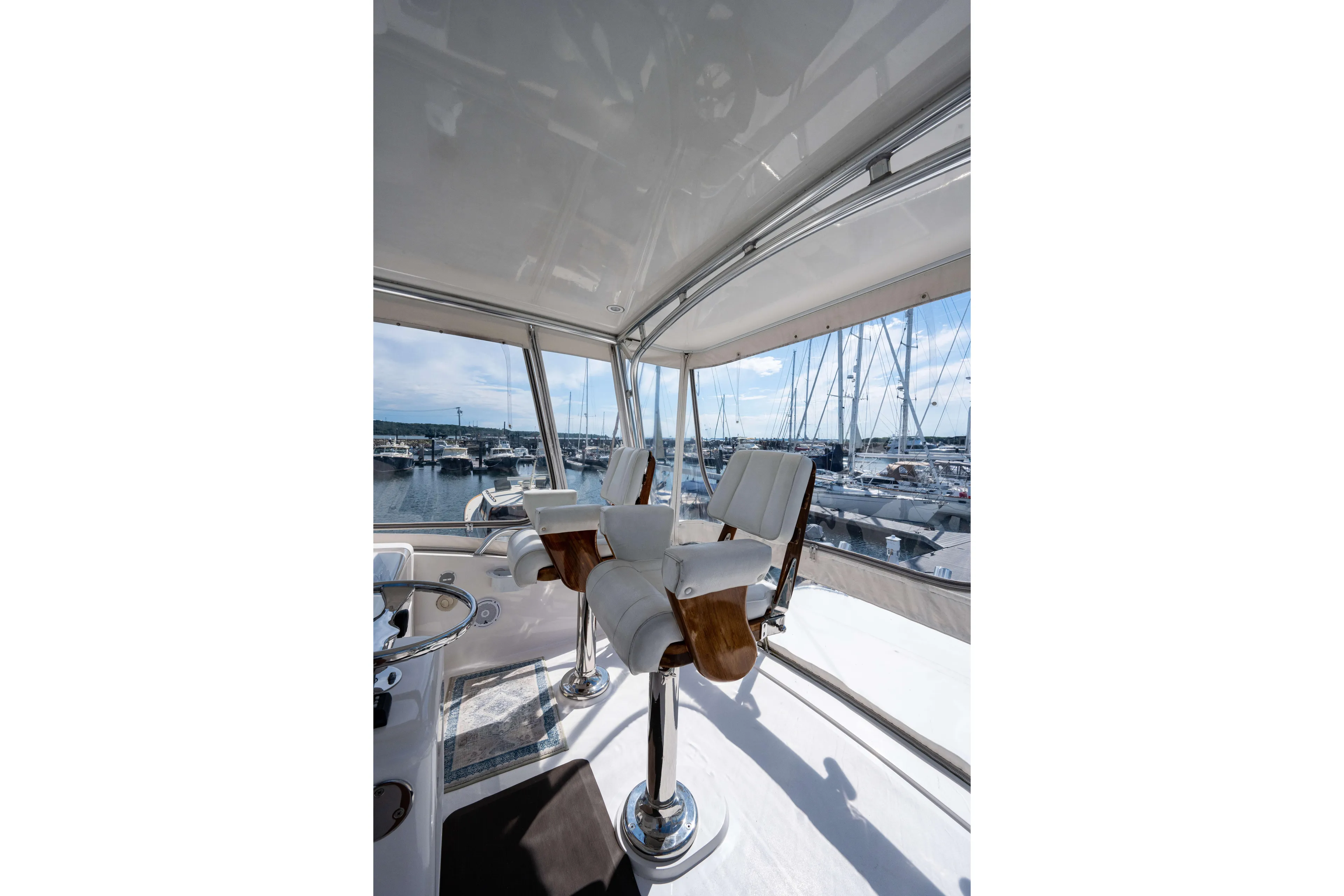 Nine Yacht Photos Pics Interior view of 2008 Bertram 570 yacht with luxurious seating and marina backdrop.