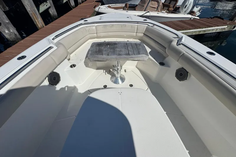  Yacht Photos Pics 2019 Boston Whaler 330 Outrage boat interior with seating and table, docked by wooden pier.