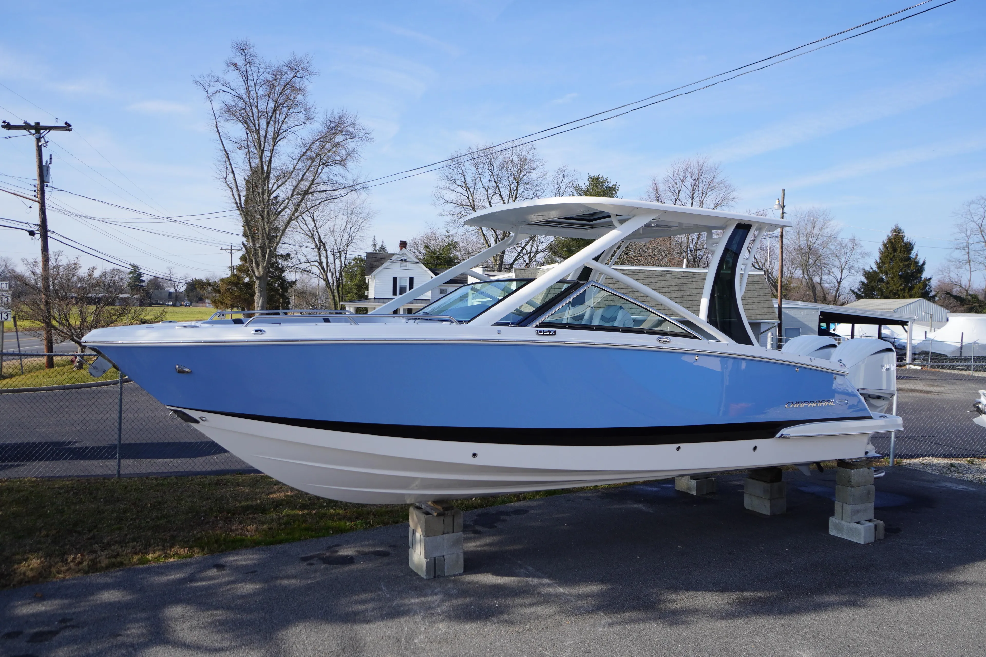 2026 Chaparral 280 OSX boat in blue, displayed outdoors on blocks.