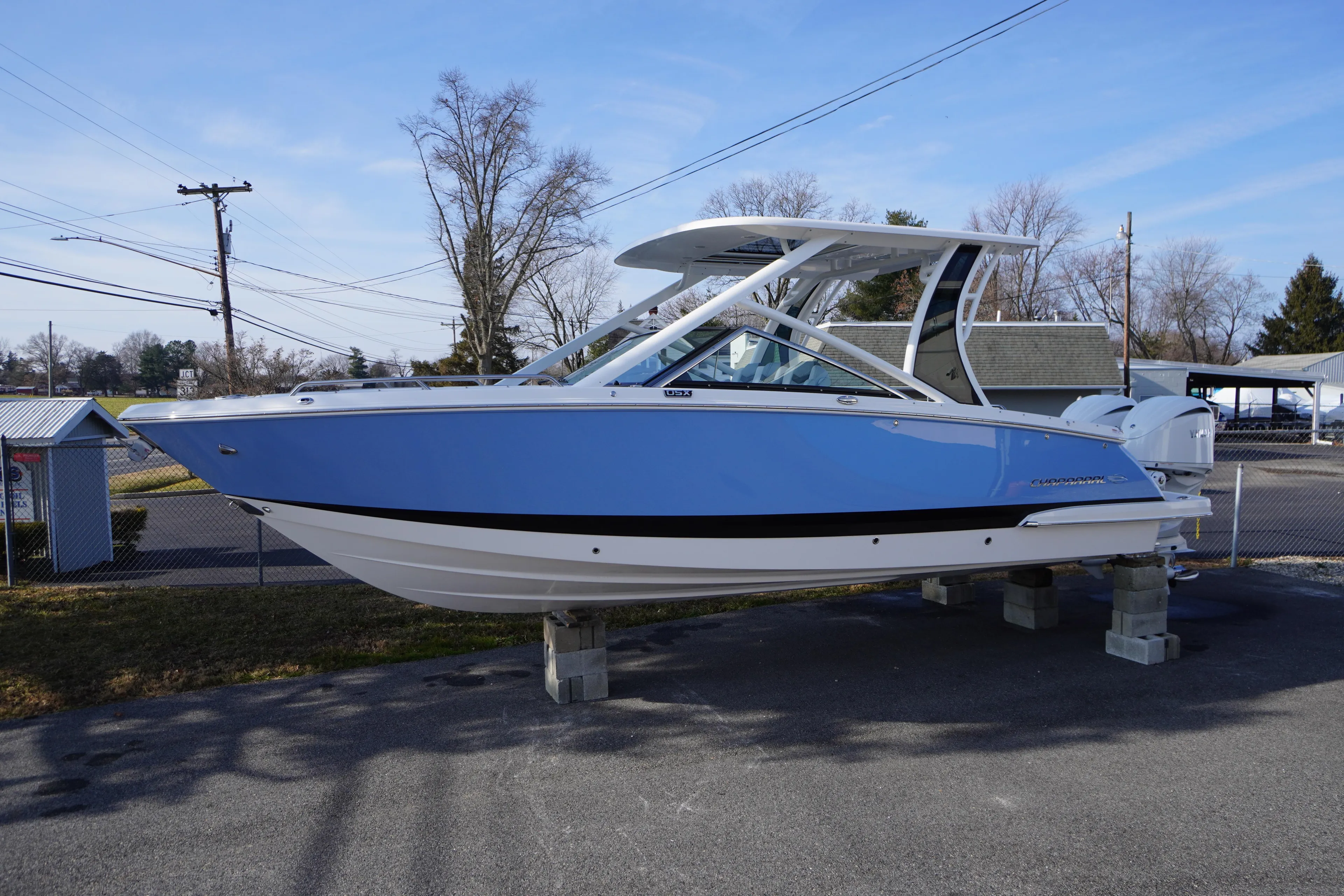 2026 Chaparral 280 OSX boat in blue, displayed outdoors on stands.