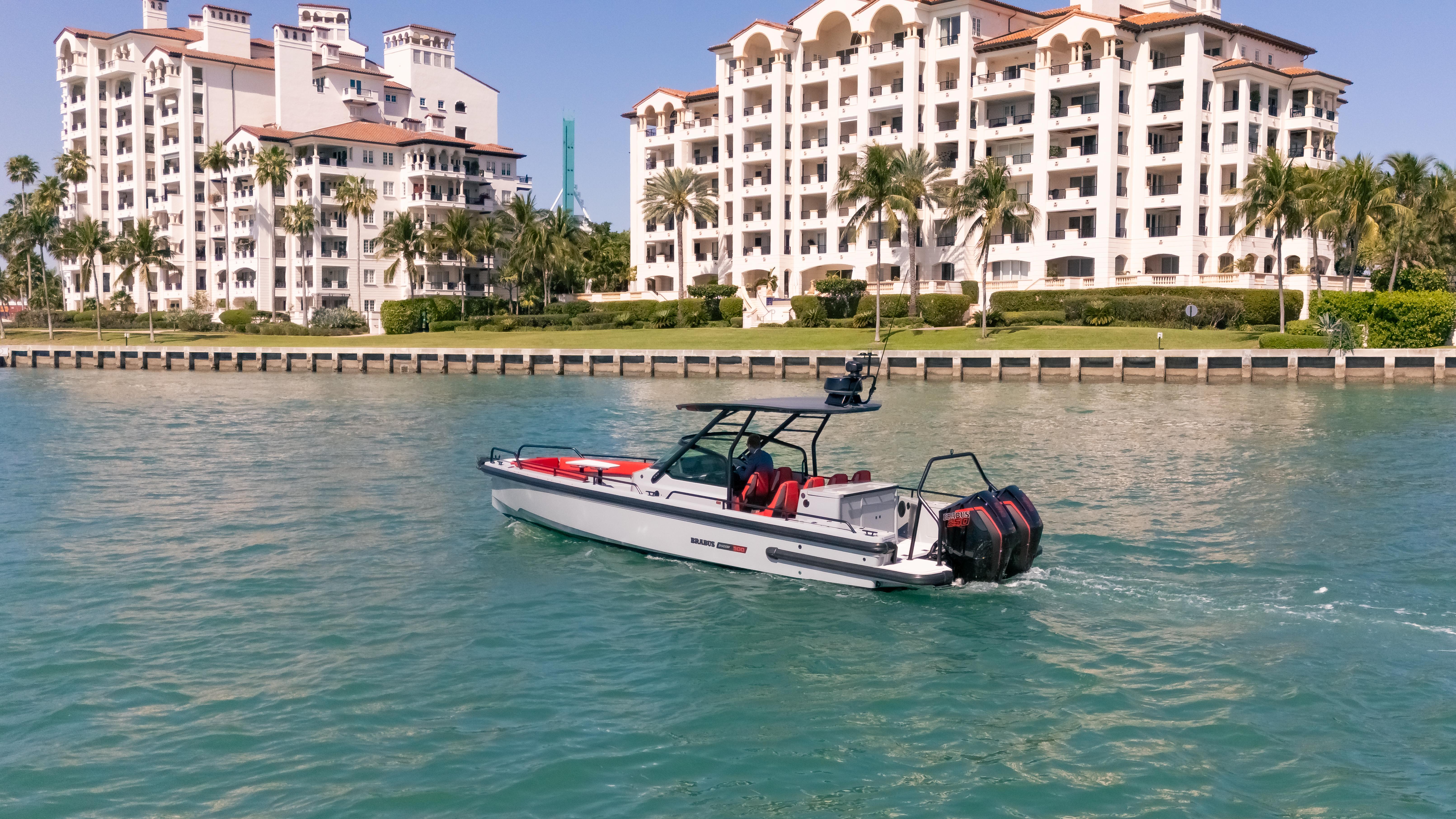 2023 BRABUS Shadow 500 T-Top boat cruising near luxury waterfront apartments.