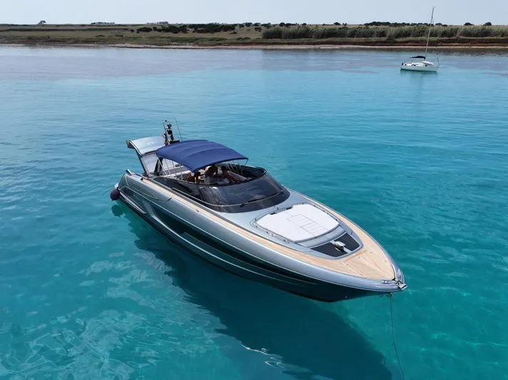 4946 Yacht Photos Pics 2023 Riva 56 Rivale yacht on clear turquoise water, featuring sleek design and blue canopy.