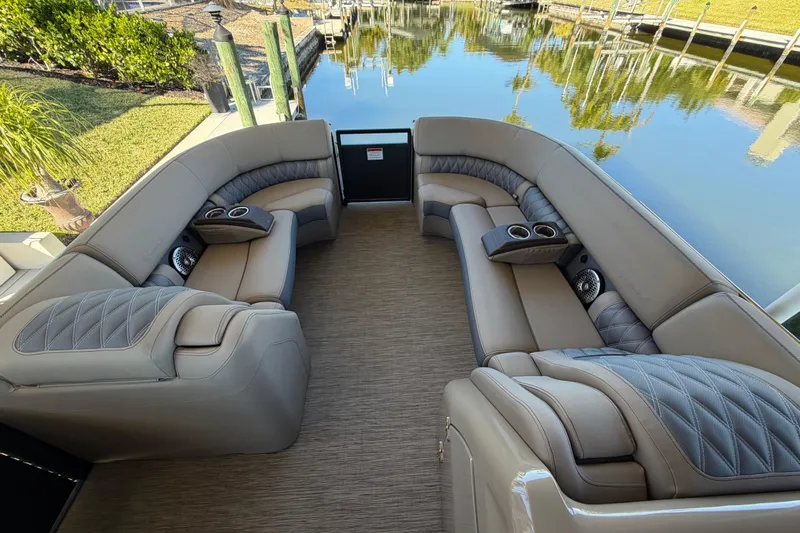  Yacht Photos Pics Luxurious seating on 2024 Bennington 25 QX Swingback pontoon boat, docked by calm waters.