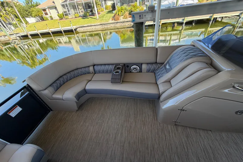  Yacht Photos Pics 2024 Bennington 25 QX Swingback interior with luxurious seating and cup holders by a serene waterfront.