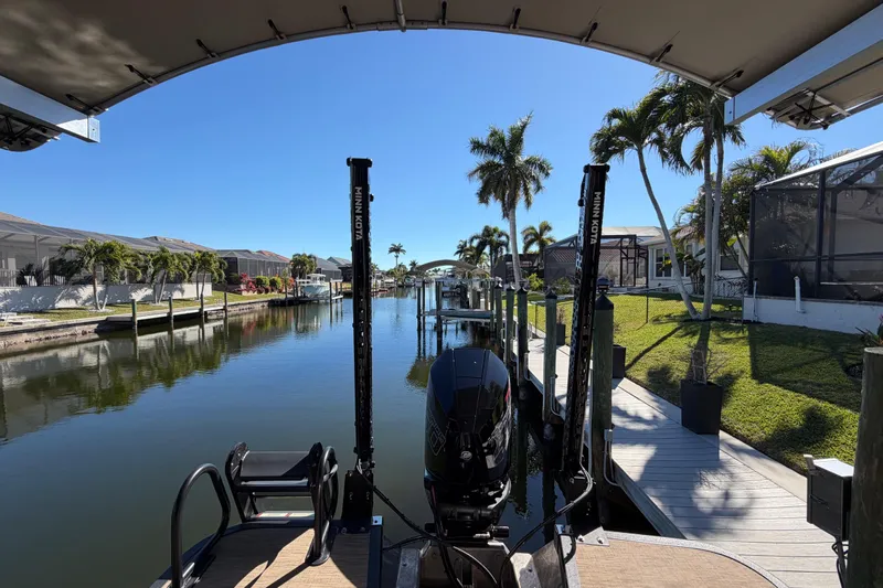  Yacht Photos Pics 2024 Bennington 25 QX Swingback on a serene canal with palm trees and docks.