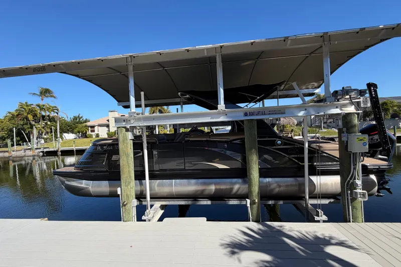  Yacht Photos Pics 2024 Bennington 25 QX Swingback pontoon boat on a lift by a dock.